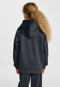 Mörkgrå hoodie med en stor huva, texturerat tyg, sänkta axlar och ribbade ärmslut och fåll, med en minimalistisk design.
