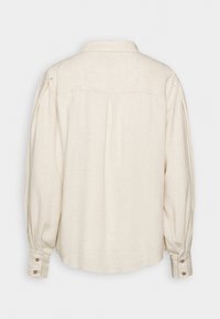 Chemise crème à manches longues avec poignets boutonnés, empiècement plissé au dos et col classique, vue de dos.