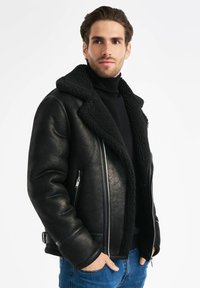 Czarna kurtka skórzana z owczej wełny z szerokim kołnierzem, zamek błyskawiczny z przodu oraz bocznymi kieszeniami. Charakteryzuje się gładką powierzchnią i teksturowaną podszewką.