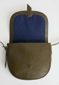 Borsa a tracolla in pelle verde oliva con chiusura a scatto rotonda, dotata di un interno in tessuto blu navy e un'esterno a superficie liscia.