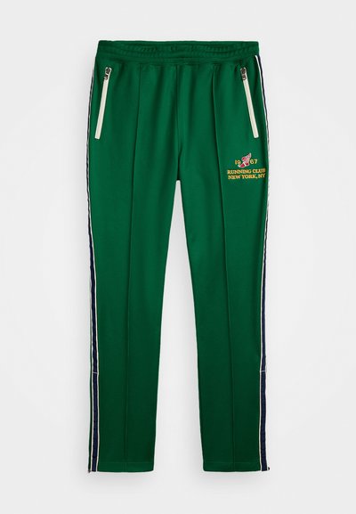 Pantaloni sport de culoare verde, cu buzunare laterale cu fermoar, detalii în dungi albastre și albe pe laterale și un logo brodat în față.