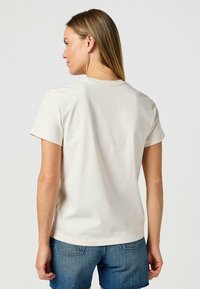 Korte mouwen, ronde hals t-shirt in lichtbeige katoen. Zachte textuur met een relaxte pasvorm, met een eenvoudig ontwerp en zonder versieringen.