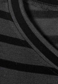 Black and gray striped knit fabric with a V-neckline, featuring a smooth texture and visible stitching along the edges.