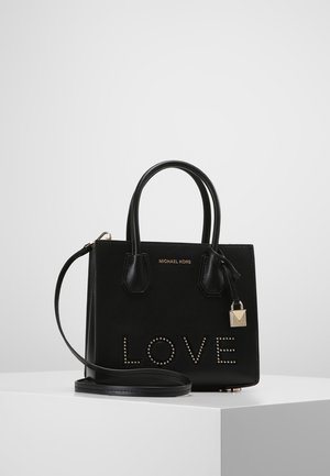 Czarna torebka Michael Kors z górnymi uchwytami, paskiem na ramię, złotym ozdobnym zamkiem i napisem „LOVE” zrobionym z okrągłych ćwieków na przednim panelu.