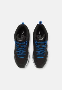 Chaussures de sport noires avec des accents et des lacets bleus, dotées d'une semelle rembourrée et d'une tige texturée pour un bon maintien. Marque Puma présente.
