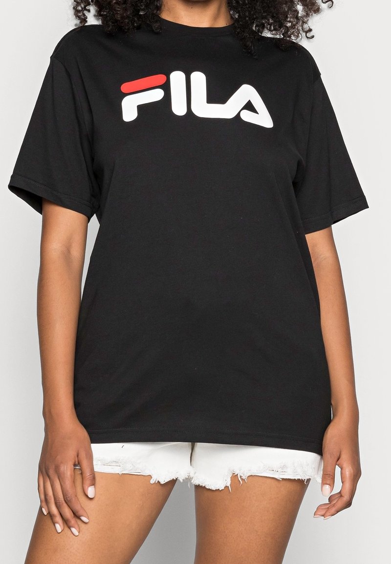 T-shirt en coton noir à manches courtes, avec un logo FILA blanc et rouge bien en vue sur la poitrine. Design classique à col rond.