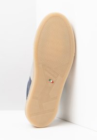 Suela de zapatilla de goma en beige con patrón de agarre texturizado, que presenta una etiqueta que indica "Hecho en Italia" y tamaño 42.