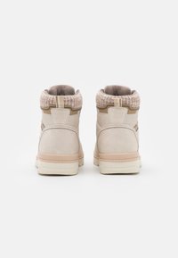 Bottines beiges avec un col tricoté texturé, un corps mat lisse et une semelle en caoutchouc contrastante. Présente un intérieur rembourré et des accents minimalistes.