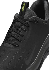 Chaussure de course noire Nike avec tissu Gore-Tex Invisible Fit, lacets noirs, et semelle amortissante Storm React.