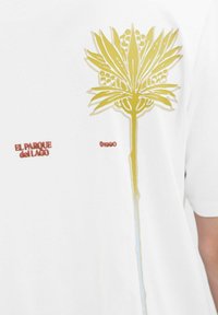 Hvid t-shirt med et stort, gult blomstermotiv med fine detaljer, samt rød tekst med teksten "EL PARQUE del LAGO" og "01900."