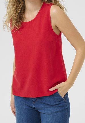 Rotes ärmelloses Oberteil, glatte Textur, lockere Passform, runder Ausschnitt, kombiniert mit blauen Jeans. Einfaches Design, keine sichtbaren Muster oder Akzente.
