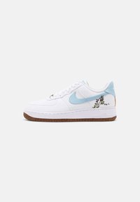 Witte Nike Air Force 1 sneaker met lichtblauwe swoosh, een bruine zool en geborduurde paarse lavendel bloemen bij de hiel op een effen achtergrond.