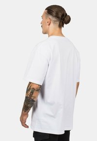 Vit bomull t-shirt med avslappnad passform, korta ärmar och rundad halsringning. Har en slät textur och inga synliga mönster eller logotyper.