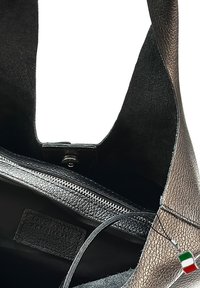 Leren tote bag met een gestructureerd oppervlak, voorzien van een zwarte binnenkant, ritsluiting en een klein Italiaans vlaggetje als bedel.