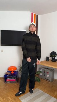 Pulover cu dungi negre și verzi, cu guler cu fermoar, asortat cu pantaloni sport negri și adidași negri. Textură netedă, croi casual.