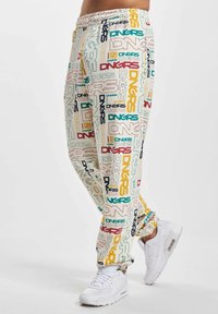 Patterned sweatpants feature a blend of colors including cream, teal, red, and yellow, with repeated "DNGRS" text. Elastic waistband and tapered design.