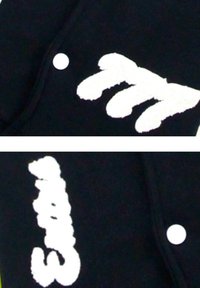 Zwarte stof met witte, textuurgevende letters; bevat een ronde witte knop. De letters hebben een penseelstrekenstijl.
