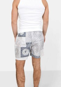 Shorts stampati in grigio e blu, con motivi paisley e floreali. Realizzati in tessuto leggero con una vestibilità comoda e tasche laterali.