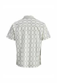 Camisa de manga corta en un gris claro con un patrón de tablero de ajedrez. Presenta un cuello abotonado y pliegues en la parte trasera para mayor libertad de movimiento.