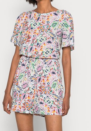 Mujer que lleva un mono corto con mangas cortas, estampado floral colorido, cintura elástica y escote redondo.