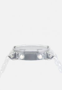 Montre en plastique transparent avec un cadran rond, deux boutons blancs et un bracelet flexible, présentant un cadran noir avec des marquages blancs.