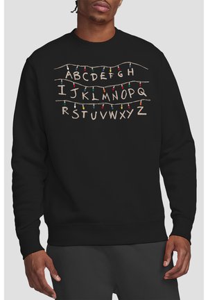 Black sweatshirt with the alphabet in three rows connected by colorful Christmas-style string lights across the chest.