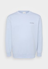 Világoskék pulóver hosszú ujjakkal, kerek nyakkivágással, bordázott mandzsettákkal és szegéllyel. A mellkason található egy kis, hímezett "Calvin Klein" logó.