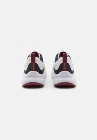 White and navy athletic shoes with a textured mesh upper, red accents, rear pull tab, and pink rubber sole.