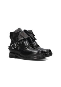 Black leather ankle boots with folded tongues, side buckle straps, and worn detailing on soles and leather.