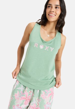 Hellgrünes Tanktop mit Rundhalsausschnitt, auf dem das Wort "ROXY" in strukturiertem, pinkem Blumen-Schriftzug gestaltet ist. Kombiniert mit Shorts im Blumenmuster.