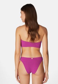 Lila stickad bikiniuppsättning med en bandeauöverdel och låg midjeunderdel med en liten knappdetalj på baksidan.