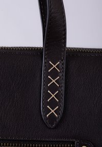 Dark brown leather handbag with a smooth texture, featuring a zip top closure and decorative beige cross-stitching on the handle.