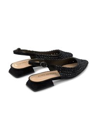 Chaussures slingback noires avec un bout pointu, ornées de clous texturés. Dotées d'un petit talon et d'une semelle intérieure lisse.