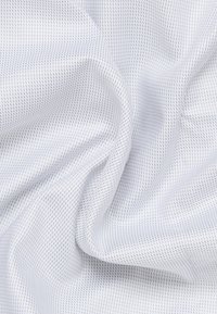 Weißes Netzgewebe mit feiner, gepunkteter Textur, in Falten drapiert, das ein leichtes und atmungsaktives Design zeigt.