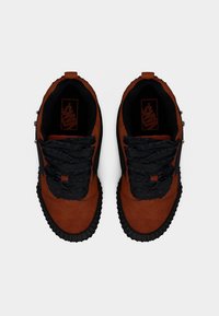 Ζευγάρι καφέ βελούδινων αθλητικών Vans με μαύρα κορδόνια με βολάν και μαύρες ραβδωτές σόλες, από πάνω σε λευκό φόντο.