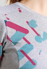 Grauer Stoff mit strukturierter Oberfläche, der abstrakte Muster in Teal und Burgunder zeigt, einschließlich runder Formen und Linien.