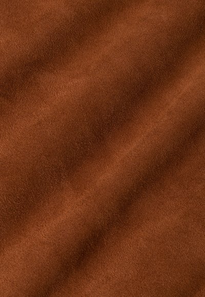 Braunes Wildleder mit einer weichen, strukturierten Oberfläche, die Falten und Knicke zeigt und das Licht sanft über seine warme Farbe reflektiert.