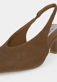 Chaussure femme en daim marron à talon bas type slingback avec bout pointu et bride ajustable visible sur fond blanc.