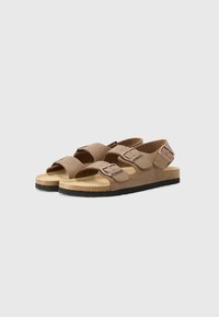 Sandale din suede maro cu două bretele reglabile, branț din plută și talpă din cauciuc negru, având un design minimalist și vârful deschis.
