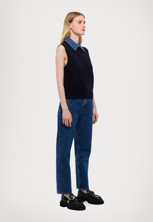 Marinemarine mouwloze gebreide top met een denim kraag, gecombineerd met hoge blauwe jeans en zwarte chunky loafers. Eenvoudig, modern ontwerp.