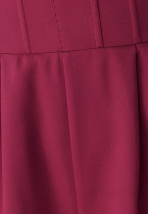 Tessuto bordeaux con una superficie liscia, caratterizzato da dettagli di cucitura verticale e un orlo svasato. Nessun motivo o accessorio visibile.