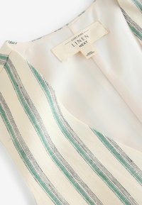 Lina segu toode vertikaalsete triipudega rohelises, tumesinises ja koorevalges. Omab silti, mis näitab materjali koostist. Sile tekstuur.