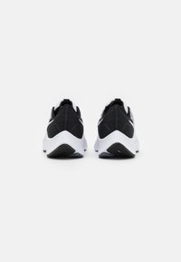 Paire de baskets noires et blanches vues de dos sur un fond blanc uni.