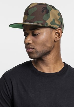 Kameraball cap i brun, grøn og tan med en flad skygge; båret med en sort crew neck T-shirt, der viser sideprofilens design.