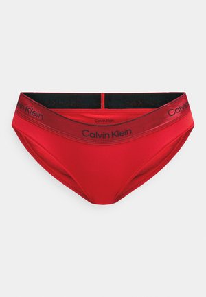 Chiloți roșii din bikini cu un brâu elastic negru pe care este inscripționat logo-ul "Calvin Klein". Textură netedă, design clasic și formă cu acoperire completă.