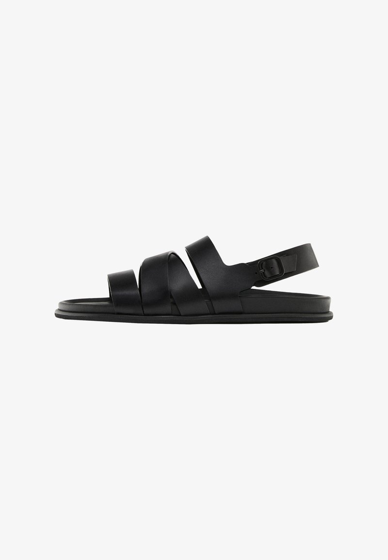Black sandals with three wide, flat straps and a back ankle strap. Made of smooth synthetic material with a minimalistic design and a flat sole.