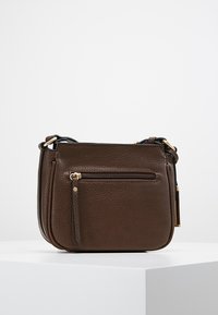 Ruskea nahkainen olkalaukku teksturoidulla viimeistelyllä, jossa etutasku vetoketjulla ja kullanväriset metalliosat. Kompakti ja suorakaiteen muotoinen malli.