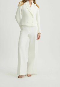 Witte dubbelgeknoopte blazer met ronde knopen en een getailleerde pasvorm, gecombineerd met wijde broekspijpen, beide met een soepele, gestructureerde stof.