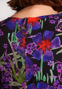 Vestido floral con fondo negro, con flores multicolores en púrpura, rojo y verde. Cierre en la parte posterior con cremallera y textura de tela suave.