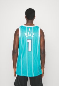 Teal koripallopaita, jossa on pystysuorat valkoiset raidat. Selässä on nimi "BALL" ja numero "1" vaaleansinisellä. Verkkomateriaalia.